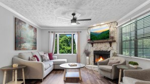 A living room with a fireplace, a sofa, a coffee table, and a TV mounted on the wall. - Lakeside Paradise Escape/Jet Ski & Kayak Adventure (Dandridge)