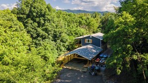 A house with a garage and a covered driveway, surrounded by dense green trees and mountains in the background. - Lakeside Paradise Escape/Jet Ski & Kayak Adventure (Dandridge)