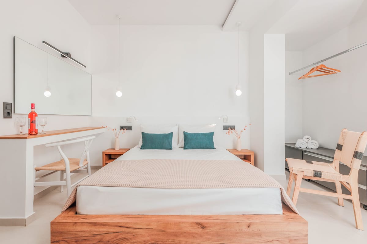 Een moderne hotelkamer met een groot bed, een houten hoofdbord, witte muren en een bureau met een stoel.