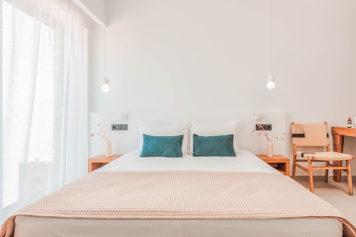 Een slaapkamer met een groot bed, twee nachtkastjes, een stoel en een bureau.
