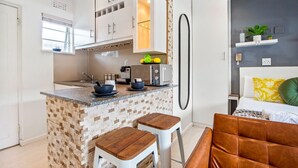 A modern kitchen with a brick island, white cabinets, and a dining area with a brown leather chair.