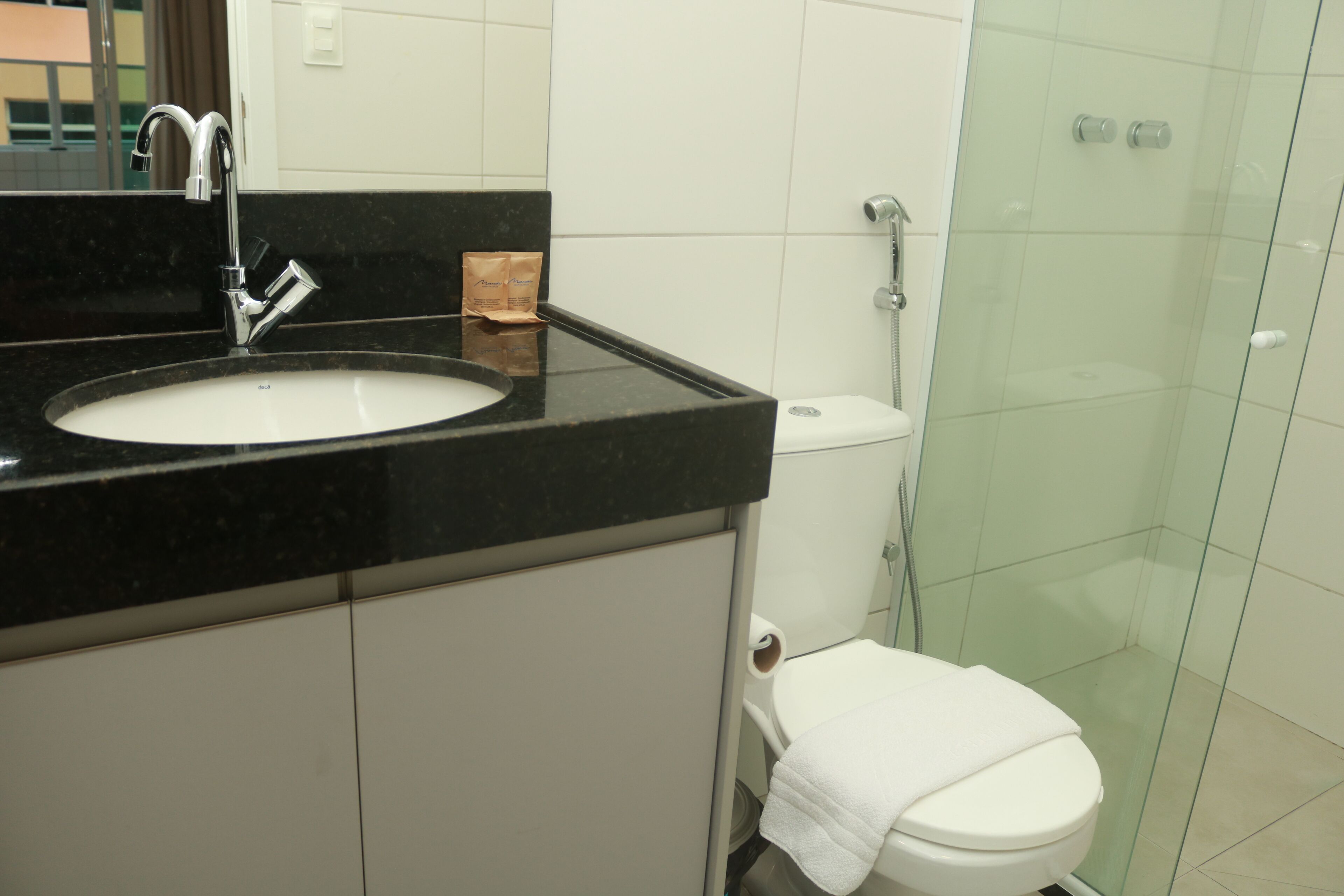 Une salle de bain avec un lavabo à vasque et un plan de toilette noir, des toilettes blanches et une douche à paroi de verre.