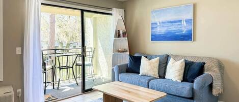 Een woonkamer met een bank, salontafel en een schilderij aan de muur.
