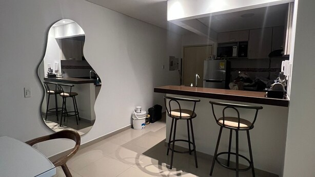 A modern kitchen with a dining area, including a bar stool setup and a table. - Rodadero Excalibur 8c (Santa Marta)