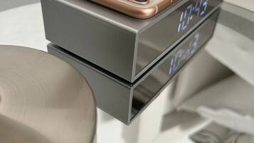 Eine moderne digitale Uhr mit einem roségoldenen Smartphone darauf, das die Uhrzeit anzeigt.
