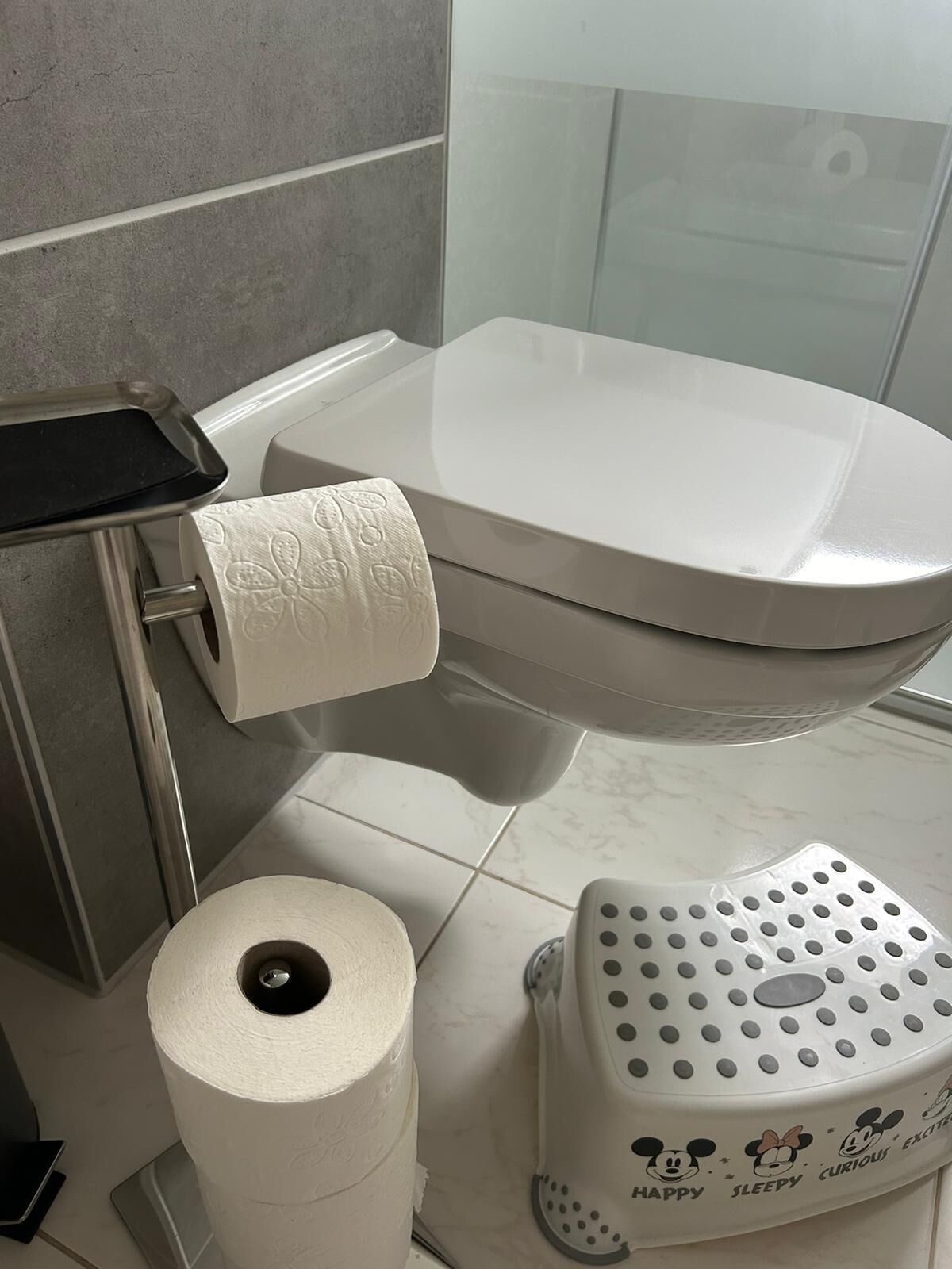 Un bagno con un water, un portasciugamani di carta e un bidet a tema Topolino.