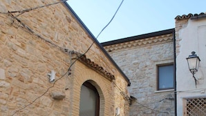 Un edificio de piedra con un arco central, un pequeño porche y una puerta de madera.