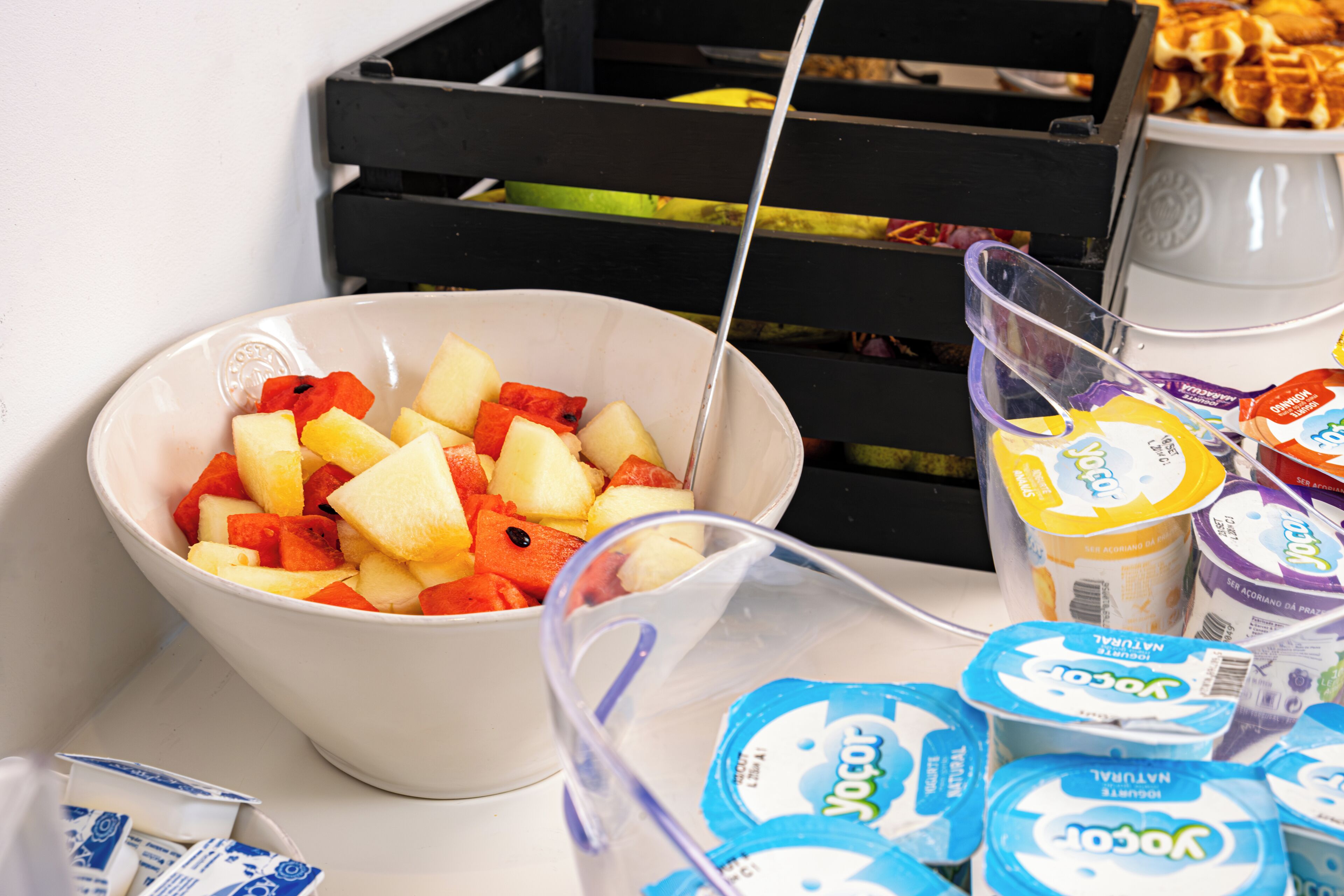 A bowl of fruit and yogurt containers.