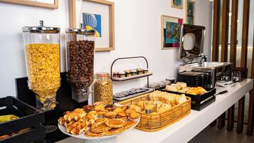 A buffet with various food items, including cereals, coffee, pastries, and bread.