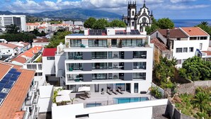 Un hôtel moderne doté d’une piscine sur le toit, de plusieurs étages et dont l’arrière-plan est dominé par une église.