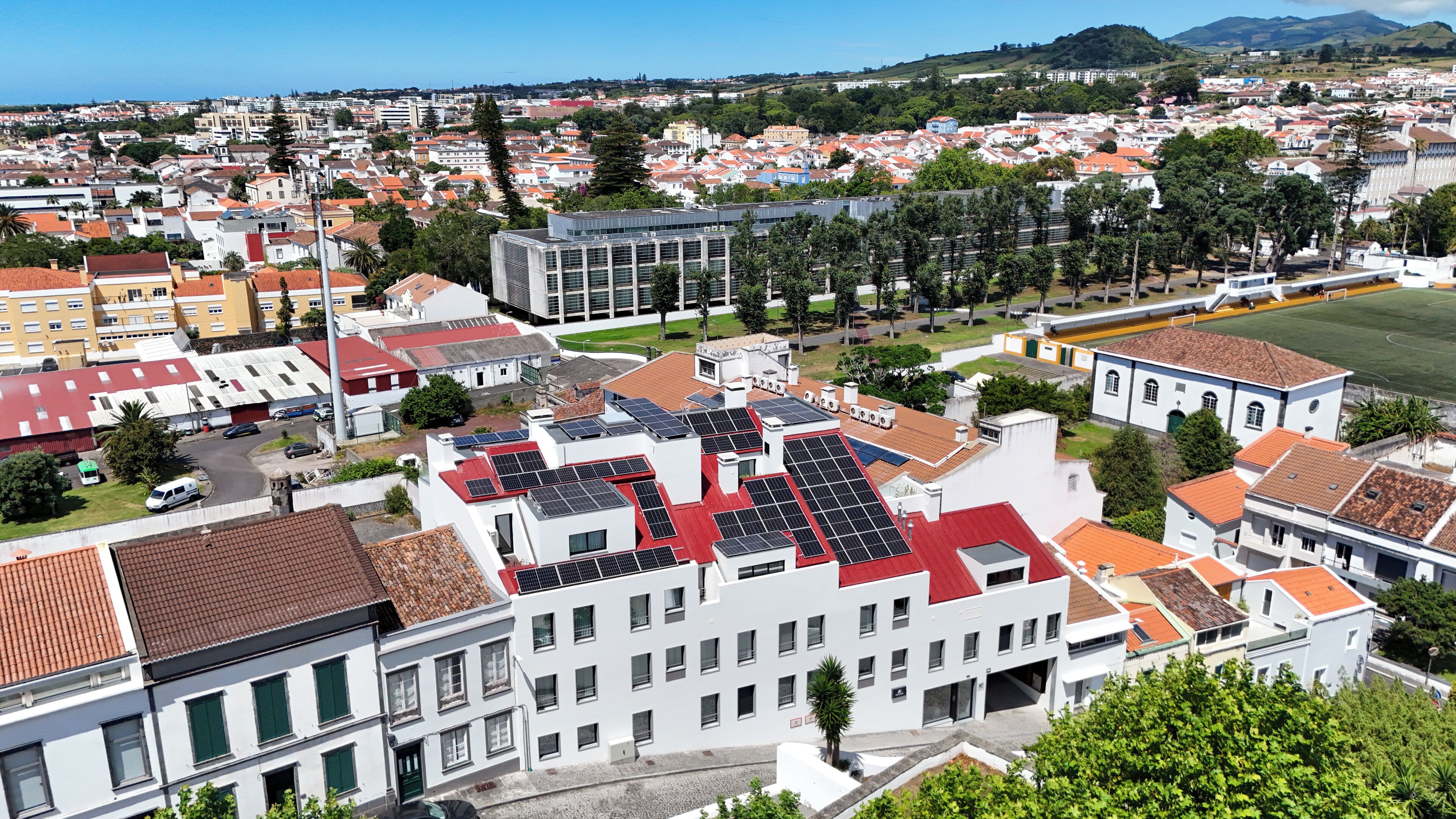 A residential area with a mix of modern and traditional buildings, including a prominent white building with solar panels on its roof.