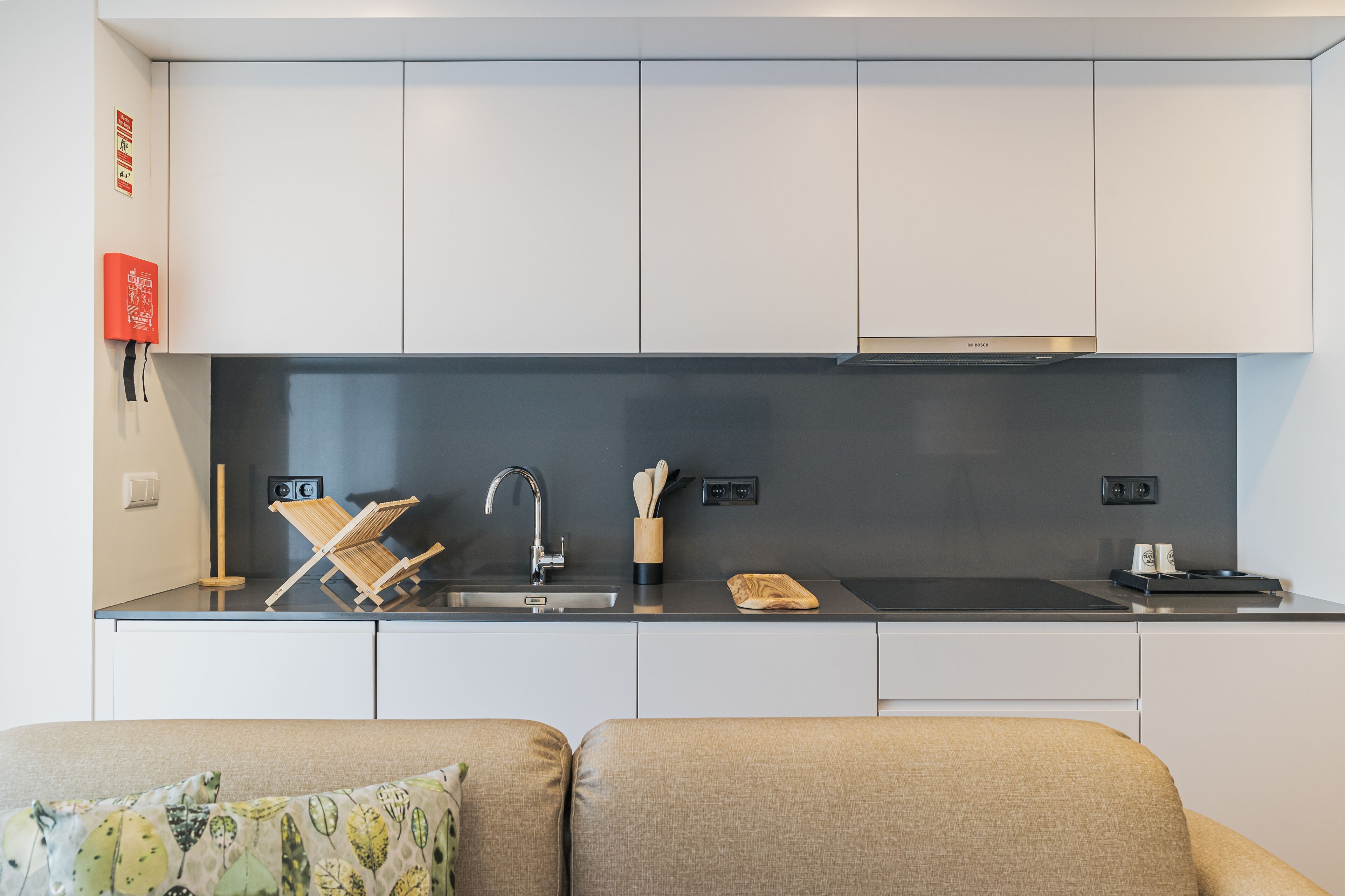 A modern kitchen with white cabinets, a black countertop, and a Bosch range hood.