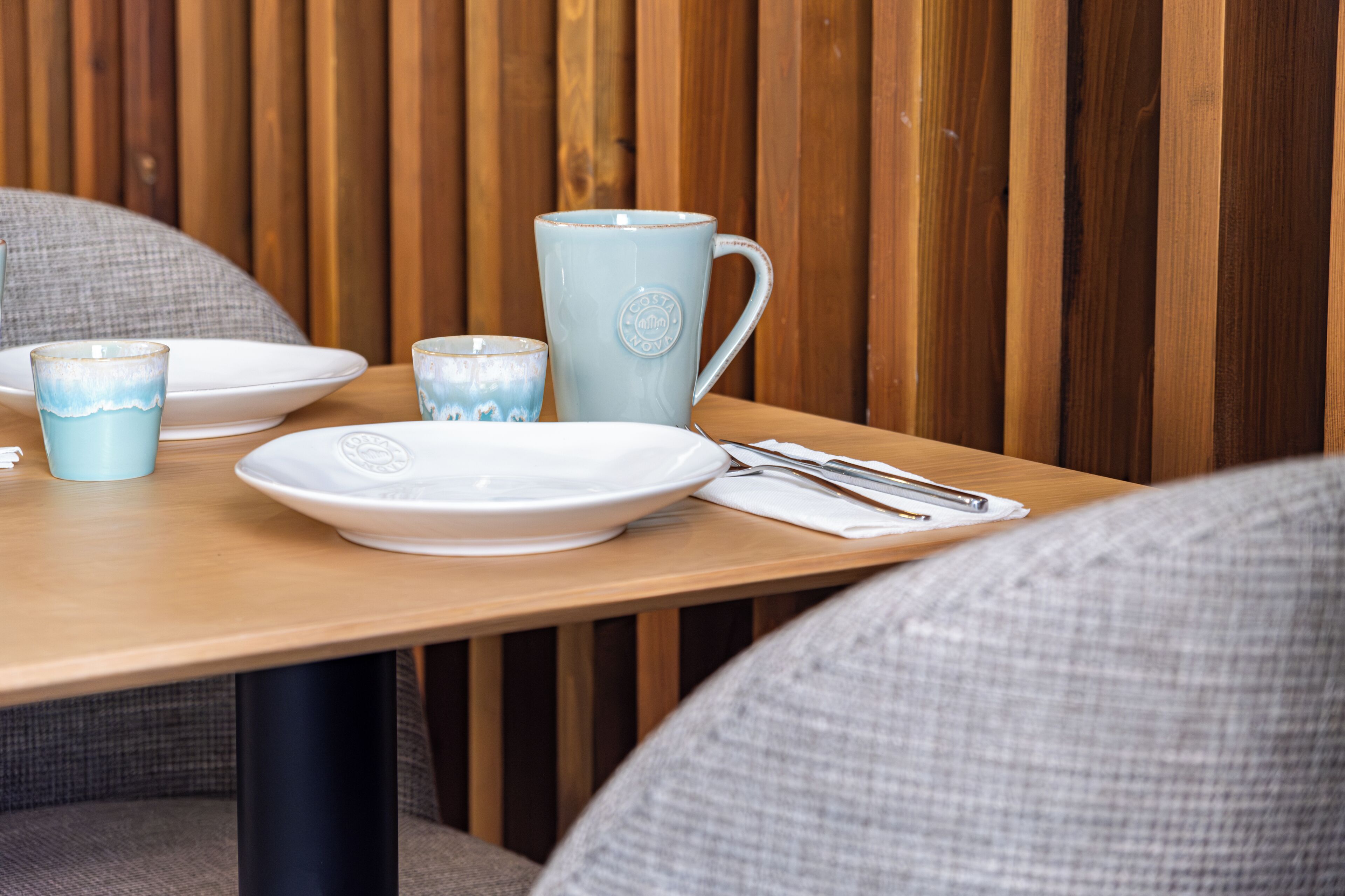 Una mesa de madera con platos, una taza y cubiertos.