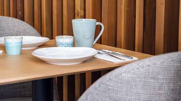 Una mesa de madera con platos, una taza y cubiertos.
