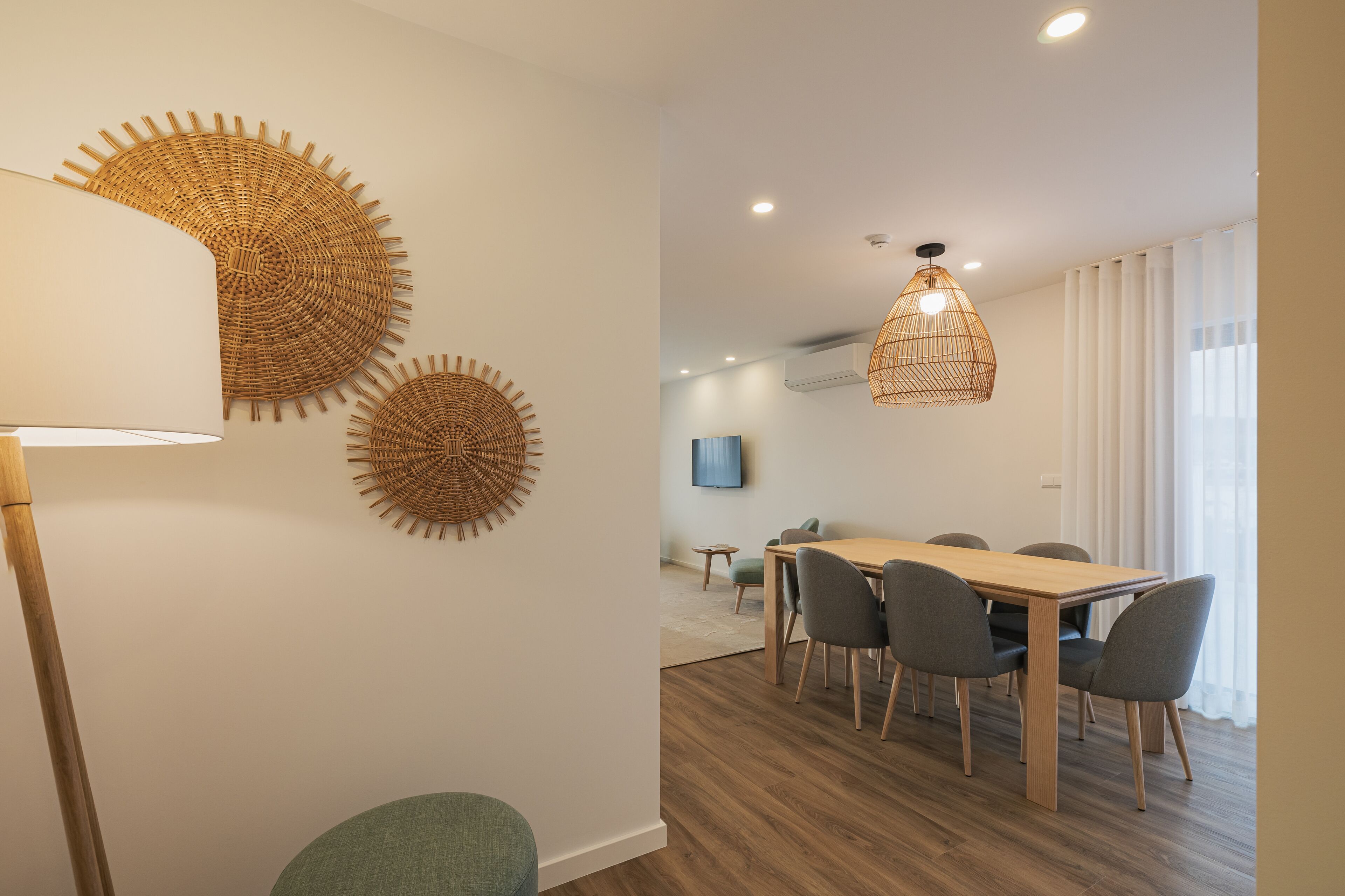 Et moderne spiseområde med et træbord og stole, en gulvlampe og dekorativ vægkunst.