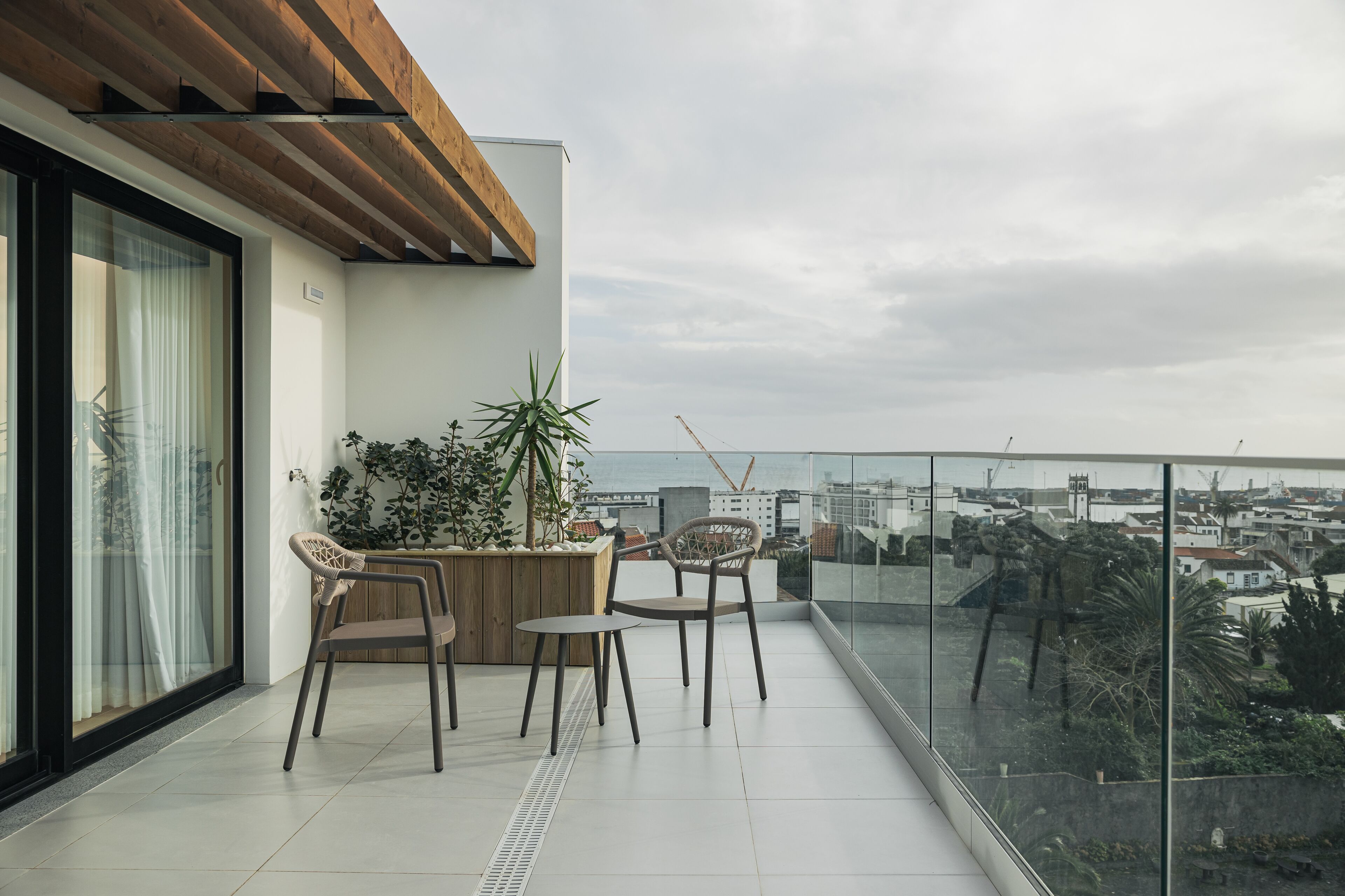 A balcony with two chairs, a small table, and a potted plant.