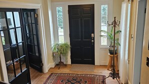 A hallway with a patterned rug, a black door, and a plant. - Spacious Private Guest Suite near Colgate (Earlville)