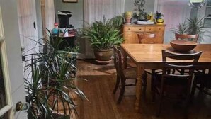 A dining area with a wooden table and chairs, potted plants, and a chandelier. - Spacious Private Guest Suite near Colgate (Earlville)