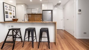 Eine moderne Küche mit einer Granit Arbeitsplatte, Edelstahlgeräten und drei schwarzen Barhocker.