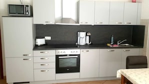 A compact kitchen with a built-in oven, microwave, and coffee maker. - Ferienhaus mit 4 Wohneinheiten für Gruppen! Hunde Willkommen! (Cuxhaven)