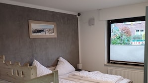 A bedroom with a bunk bed, a single bed, a framed picture on the wall, a window with blinds, and a ceiling light fixture. - Ferienhaus mit 4 Wohneinheiten für Gruppen! Hunde Willkommen! (Cuxhaven)