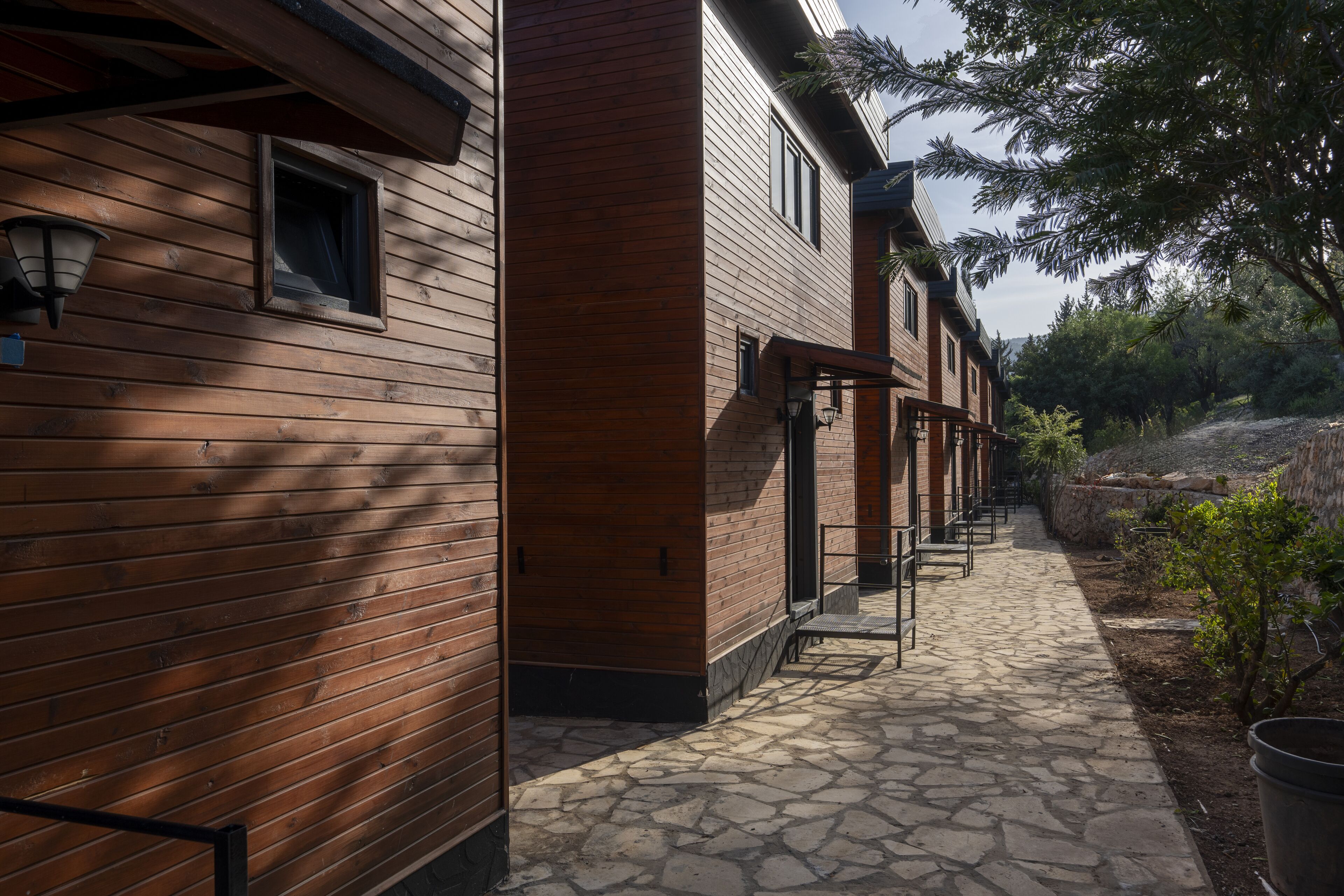 A wooden building with a stone pathway leading to a covered outdoor seating area.