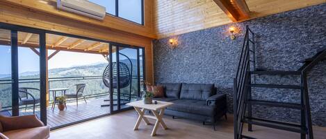 A spacious room with a balcony, a sofa, a table, and a ladder.