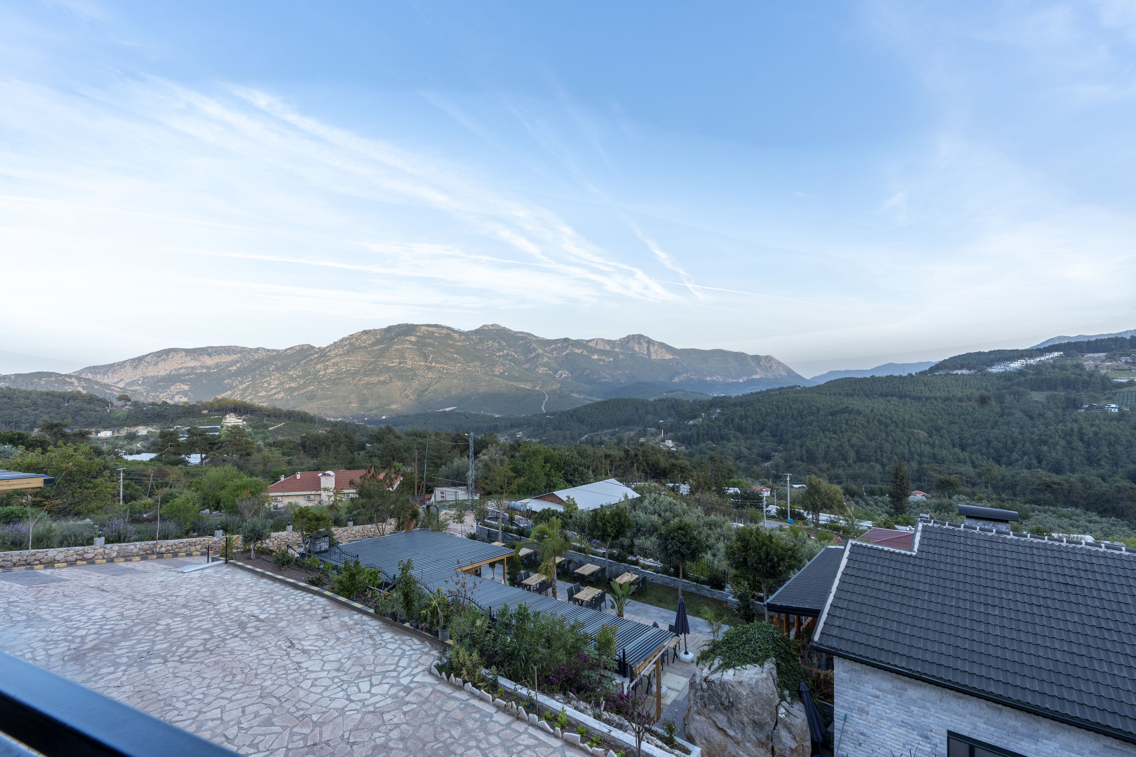 A mountainous landscape with a view of a residential area, including houses and a paved patio area.