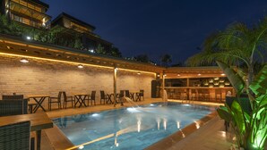 A swimming pool with lounge chairs and a bar area, surrounded by a brick wall and palm trees. - La Veranda Villas (Kumluca)