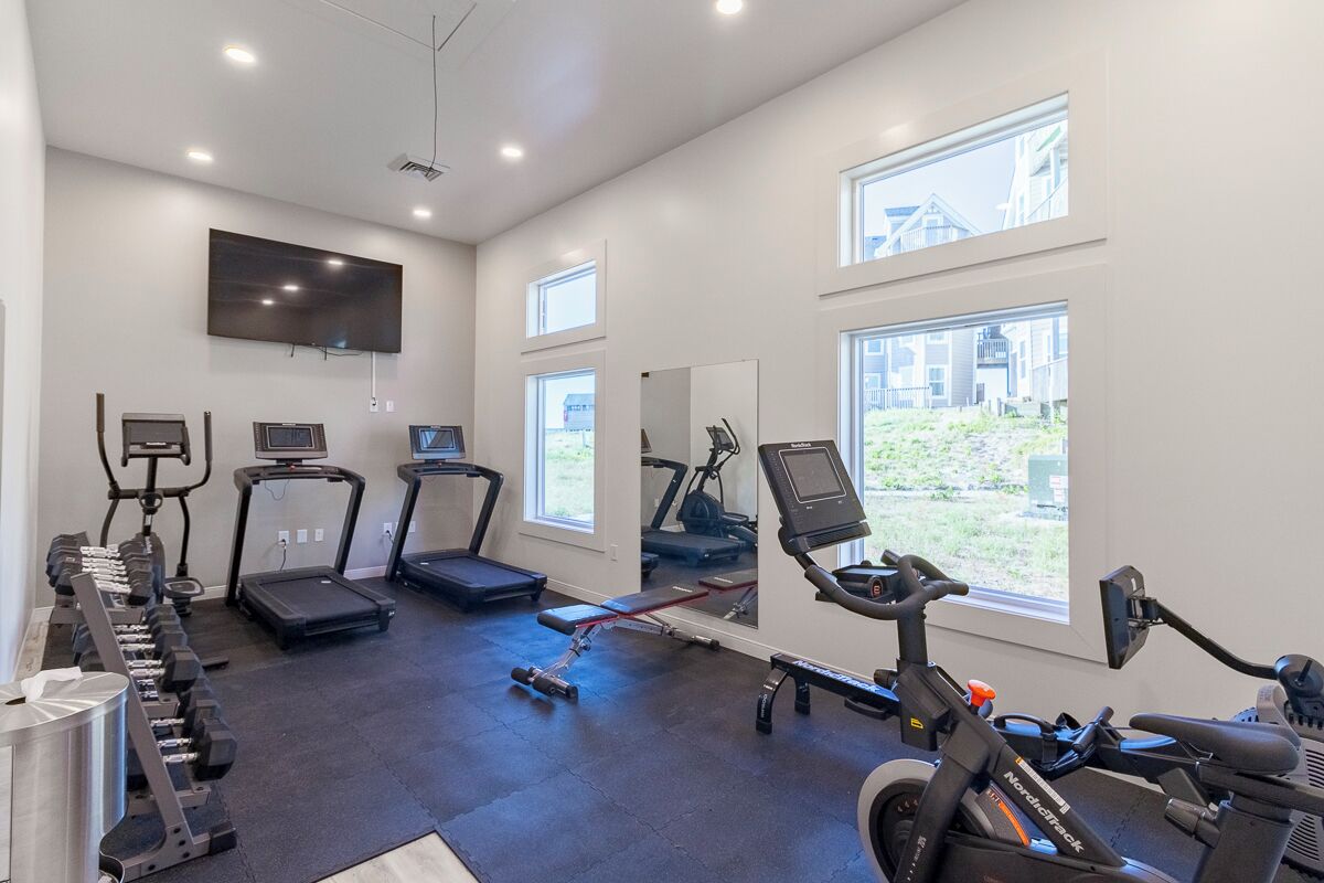 A gym with treadmills, elliptical machines, and free weights.