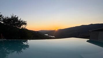 Un ciel dégagé avec un coucher de soleil sur une étendue d’eau, le tout entouré de collines.