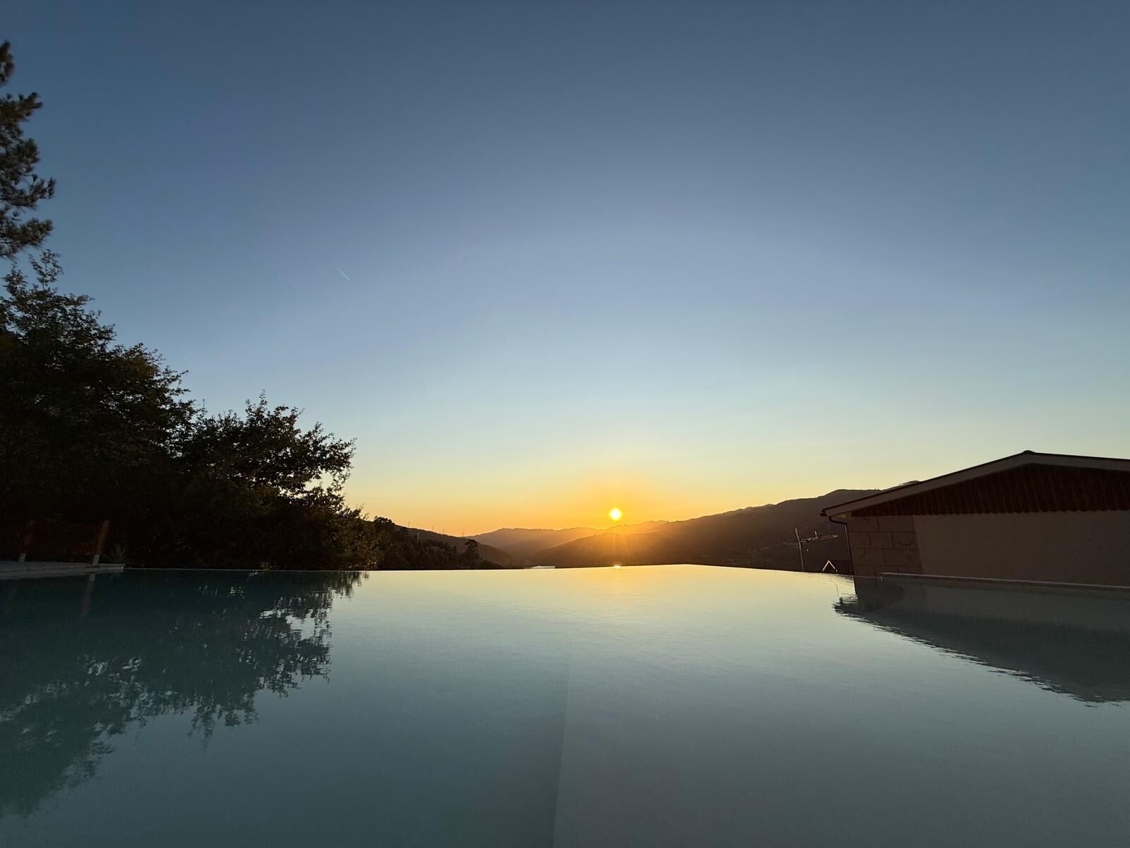Un ciel dégagé, avec un coucher de soleil sur une étendue d’eau calme qui reflète le ciel.