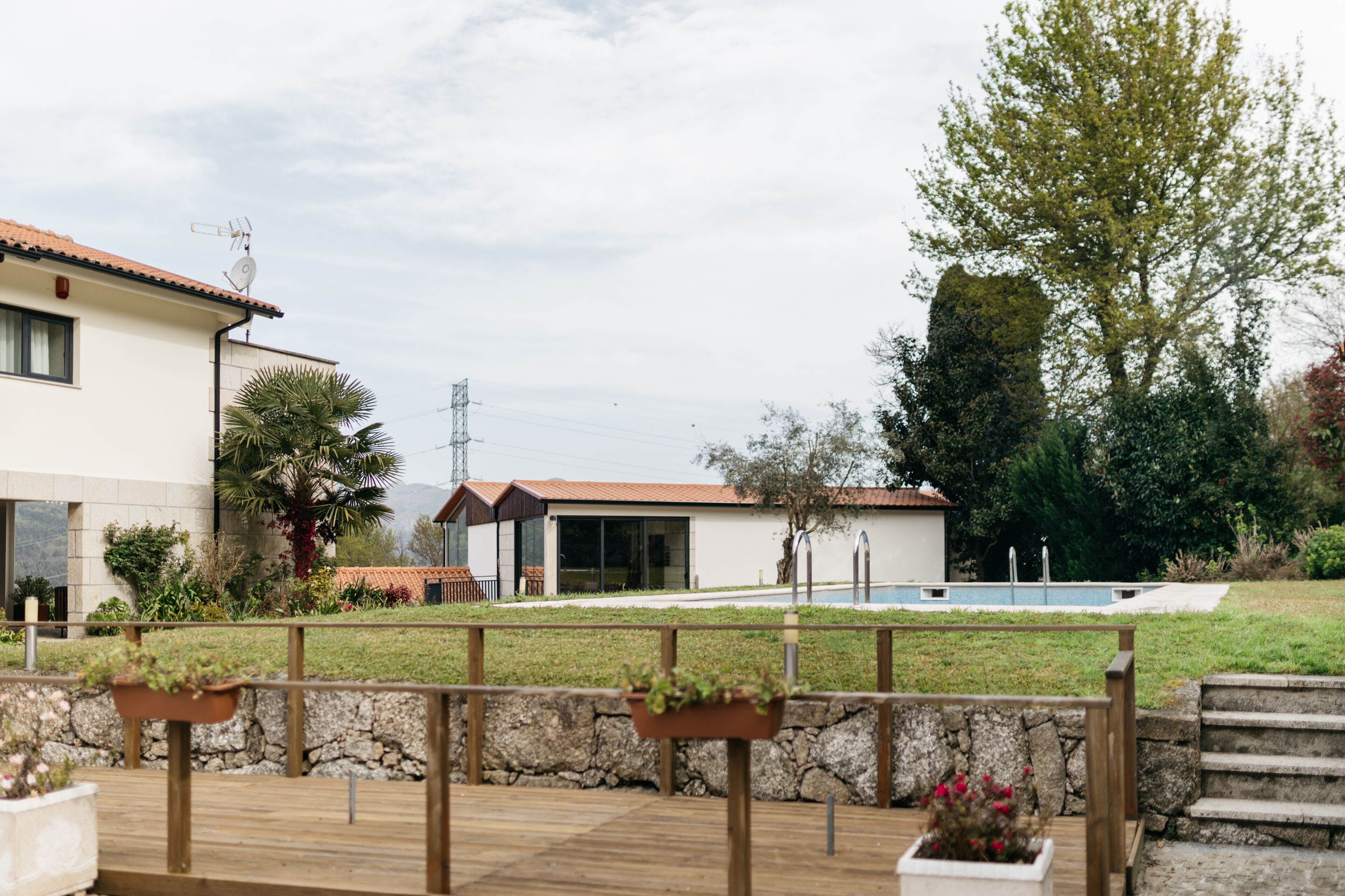 A modern house with a swimming pool, a stone wall, and a wooden deck.