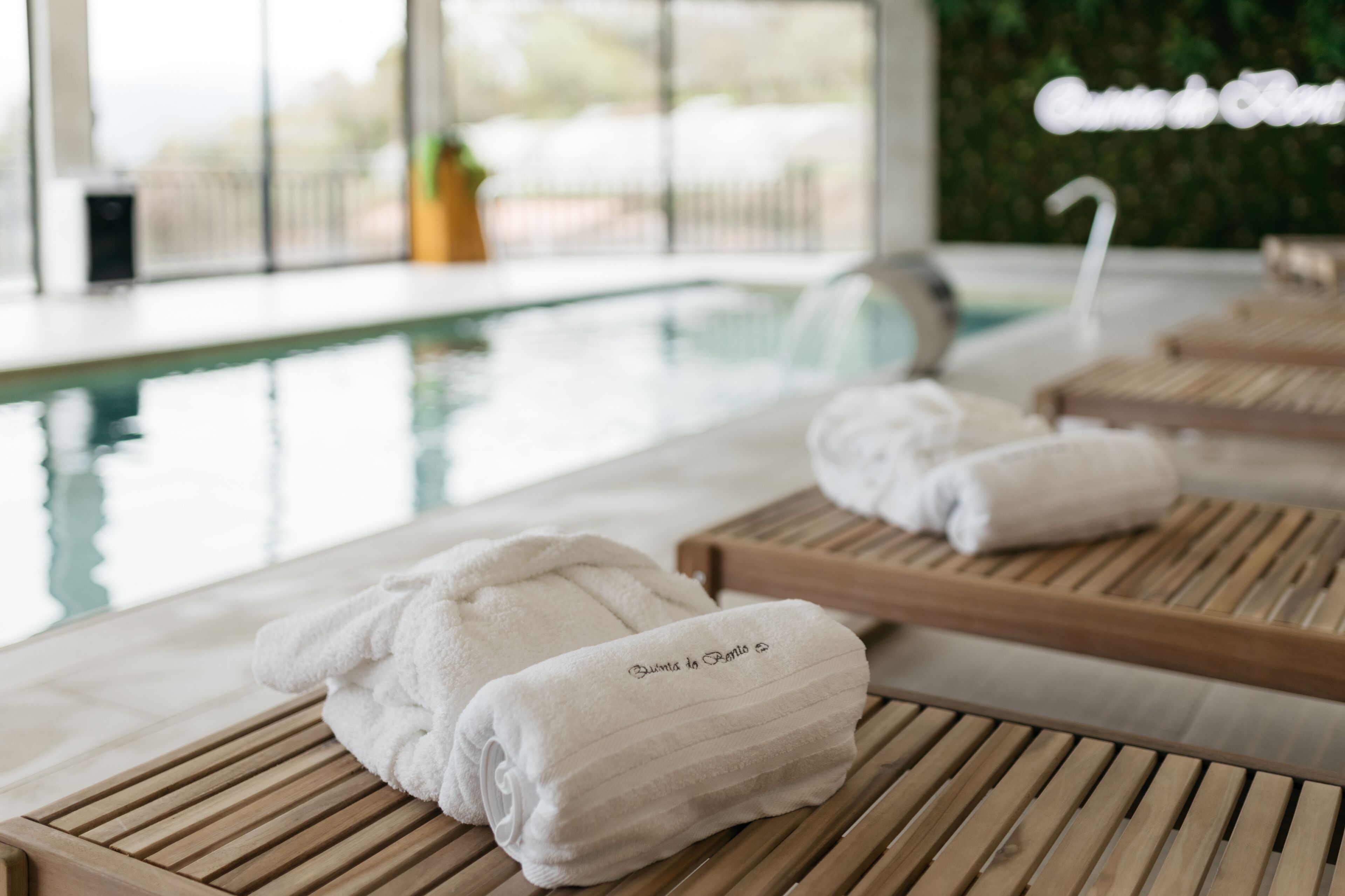 Un espace aménagé au bord de la piscine, avec des chaises longues en bois et des serviettes blanches ornées de l’inscription « Bimini to Bimini ».