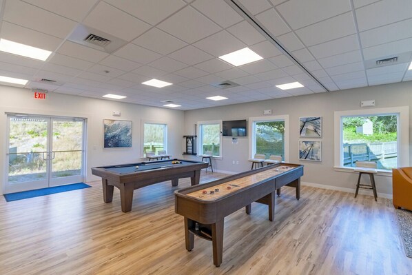 Une salle de billard équipée de deux tables de billard, d’une table de jeu de palet et d’une porte donnant sur l’extérieur.
