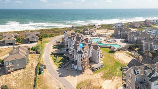 A coastal residential area with houses, a swimming pool, and a pier. - Gorgeous ocean views from this stunning, updated coastal condo! (Duck)