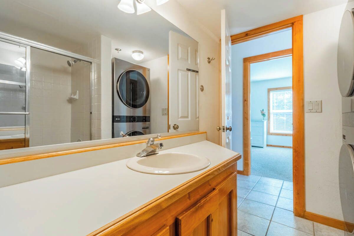 Un bany amb un mirall gran, un lavabo i una porta que dona a una altra habitació.