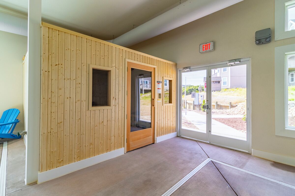 A hotel entrance with wooden paneling, a blue chair, and a glass door leading outside.