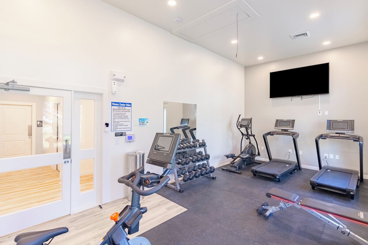 Una palestra con tapis roulant, ellittiche e una rastrelliera per pesi.