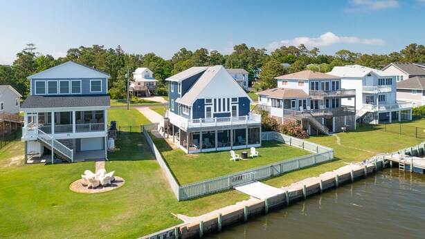 Une propriété située au bord de l’eau, comprenant plusieurs maisons, un quai et une pelouse.