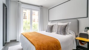 A modern hotel room with a large bed, a bedside table, and a view of the outside.