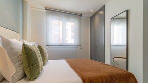 Een hotelkamer met een bed, kussens, een raam en een spiegel.