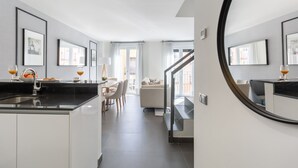Una cucina moderna con un piano di lavoro nero, mobili bianchi e un'area pranzo con tavolo e sedie.