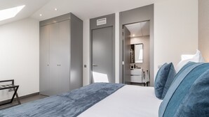 Una camera da letto moderna con un letto grande, un armadio, un bagno con uno specchio e una scrivania.