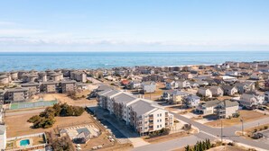 A coastal residential area with a mix of single-family homes and apartment buildings, a clear view of the ocean, and a tennis court. - Great Coastal Condo in the heart of Kill Devil Hills NC! (Kill Devil Hills)