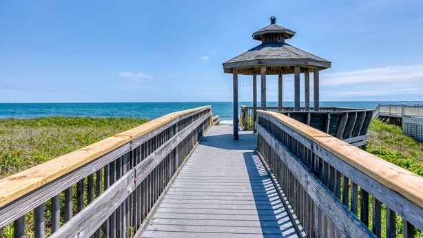 A wooden boardwalk leading to a gazebo by the sea. - Great Coastal Condo in the heart of Kill Devil Hills NC! (Kill Devil Hills)