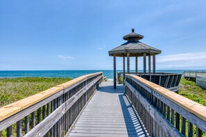A wooden boardwalk leading to a gazebo by the sea. - Great Coastal Condo in the heart of Kill Devil Hills NC! (Kill Devil Hills)