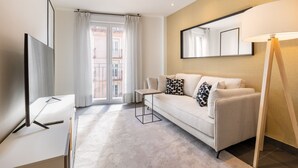 A modern hotel room with a sofa, a small table, a standing lamp, and a large window with curtains. - Amazing new duplex for 4 (Madrid)