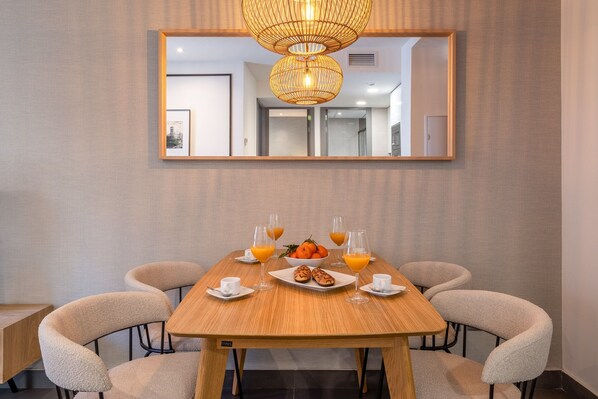 Un comedor con una mesa de madera, seis sillas y un espejo grande arriba.