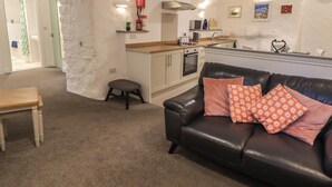 A cozy living room with a black leather sofa and a small wooden table. - Le Durkestrete Cellar (Haverfordwest)